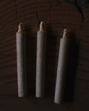 Three cylindrical candles with wicks on a dark textured background