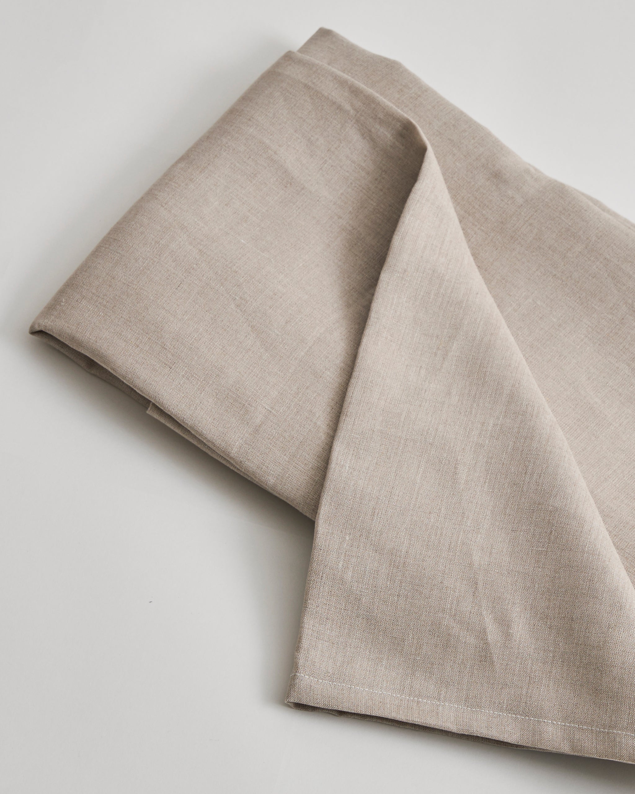 Folded unbleached flat sheet on a light gray background