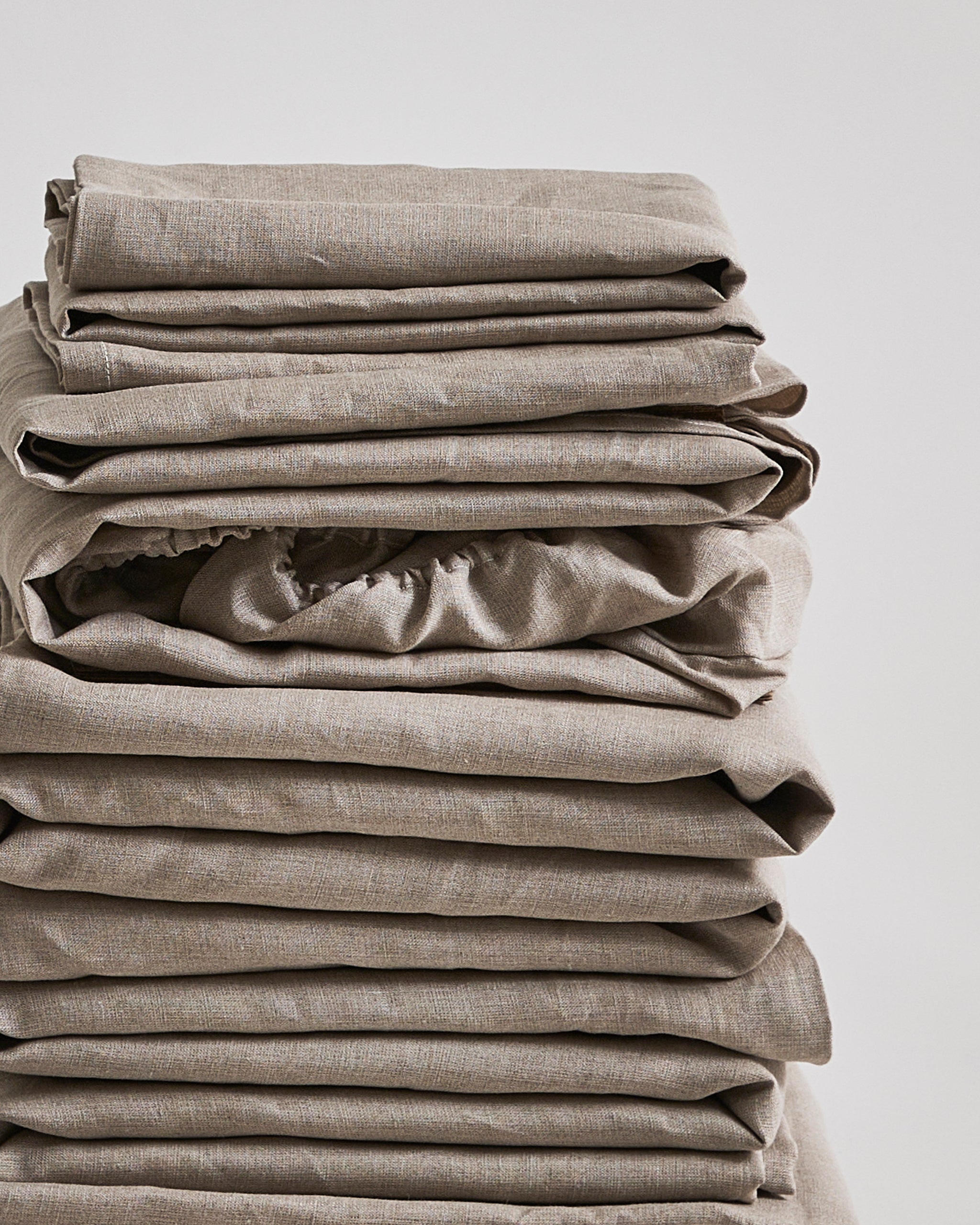 Stack of unbleached linen folded sheets by Iwata on a gray background