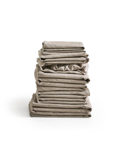 Stack of unbleached linen folded sheets by Iwata on a white 