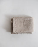 Folded unbleached linen pillowcase on a gray background