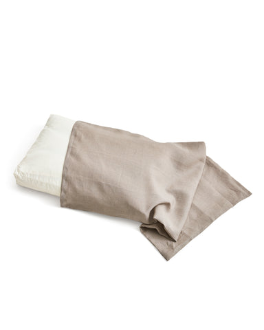 White pillow with unbleached linen pillow sheet on a white background
