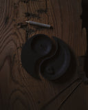 Cast iron candle holder and incense holder in yin and yang shape from Nezen Box Set by Iwata on a wooden background