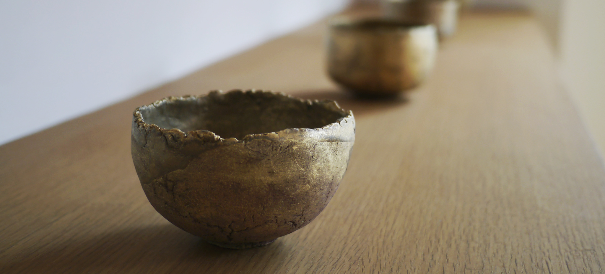 Gold chawan on display on wood shelf
