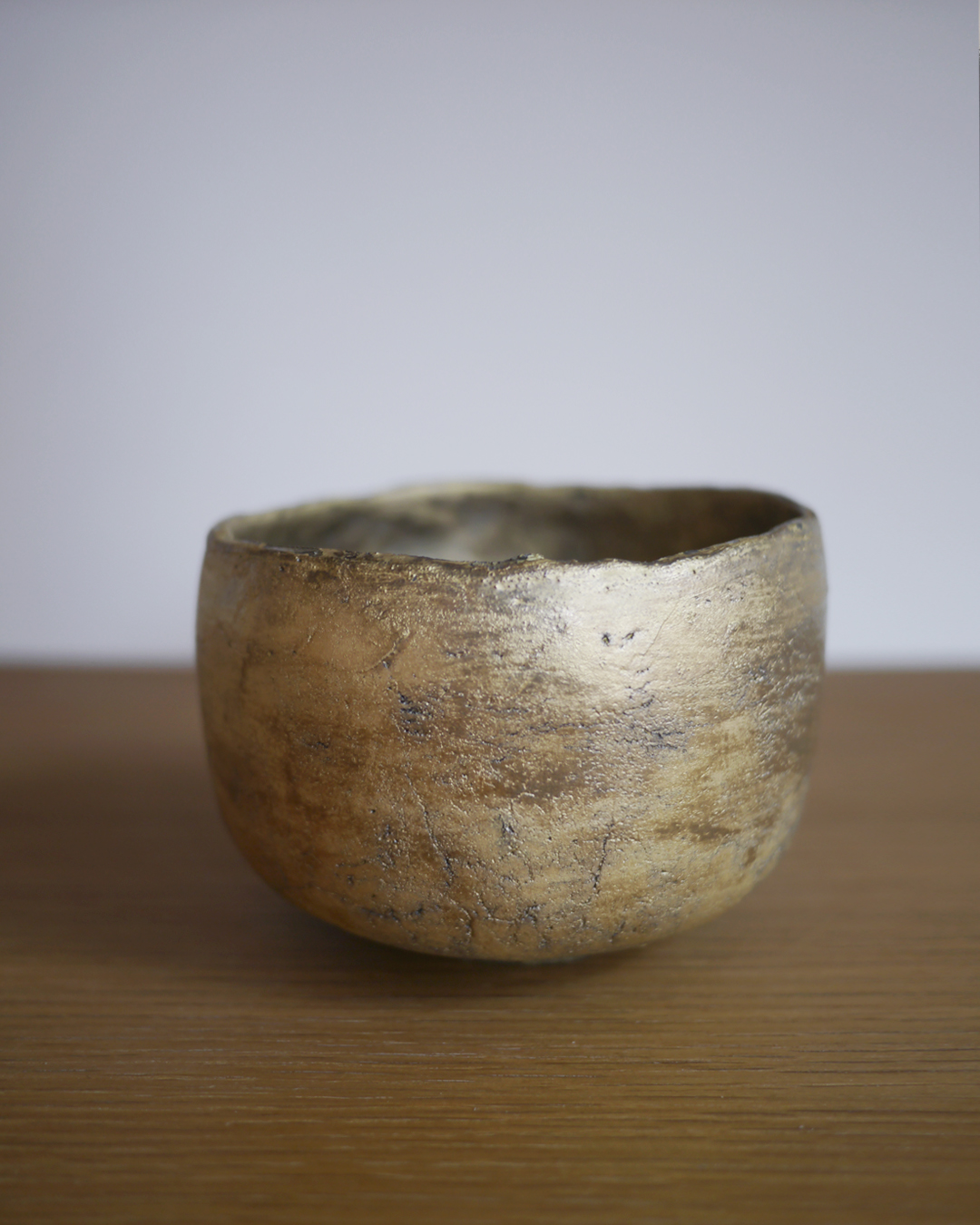 Close up of gold chawan on display on wood shelf