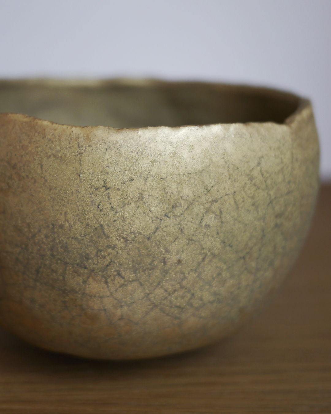 Close up of gold chawan on display on wood shelf