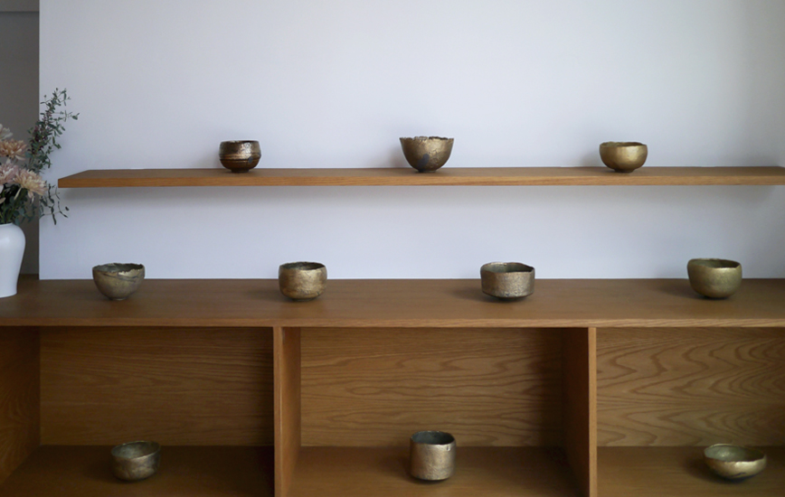 Gold chawan on display on wood shelf
