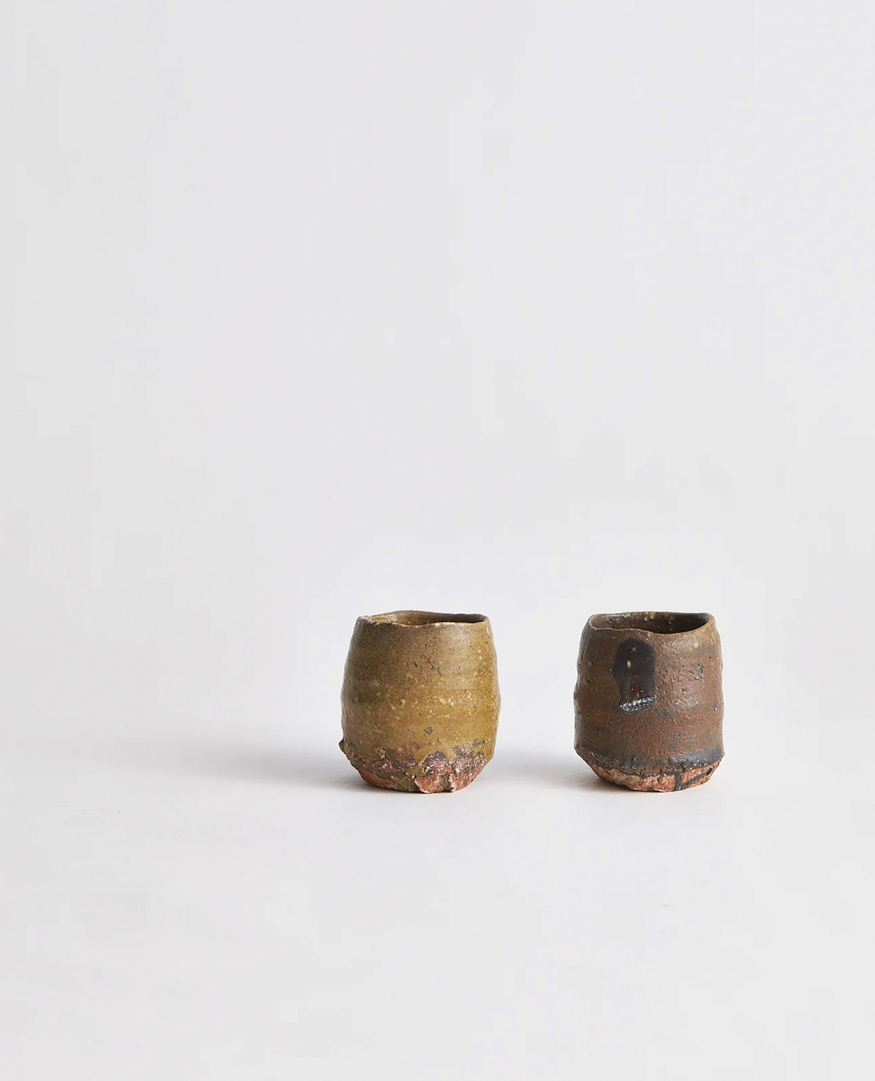 Two Anagama Ochre Cups in warm yellow, brown tones by Keisuke Iwata on a gray background