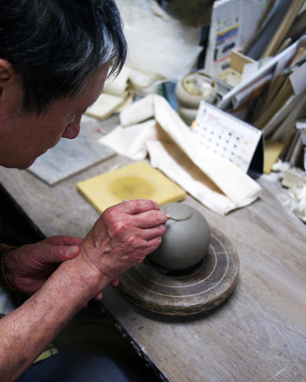 Keisuke Iwata in his ceramics studio building a teapot close up