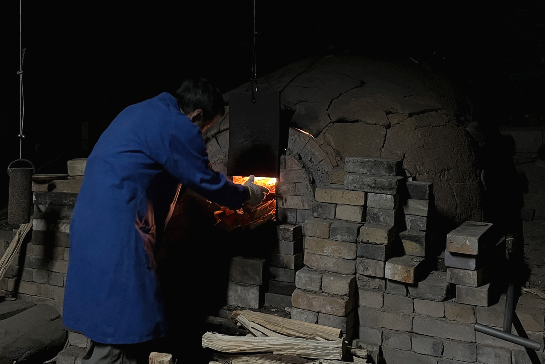 Keisuke Iwata adding pine wood logs to the anagama kiln opening
