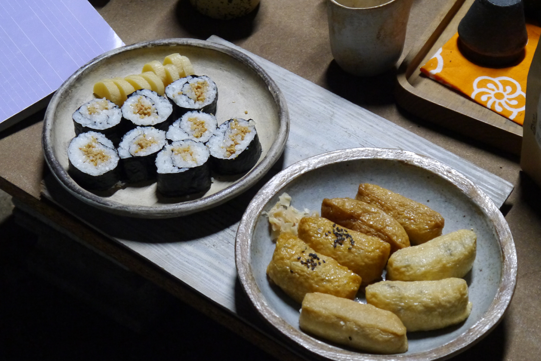 Two plates filled with snack food of sushi and onigiri
