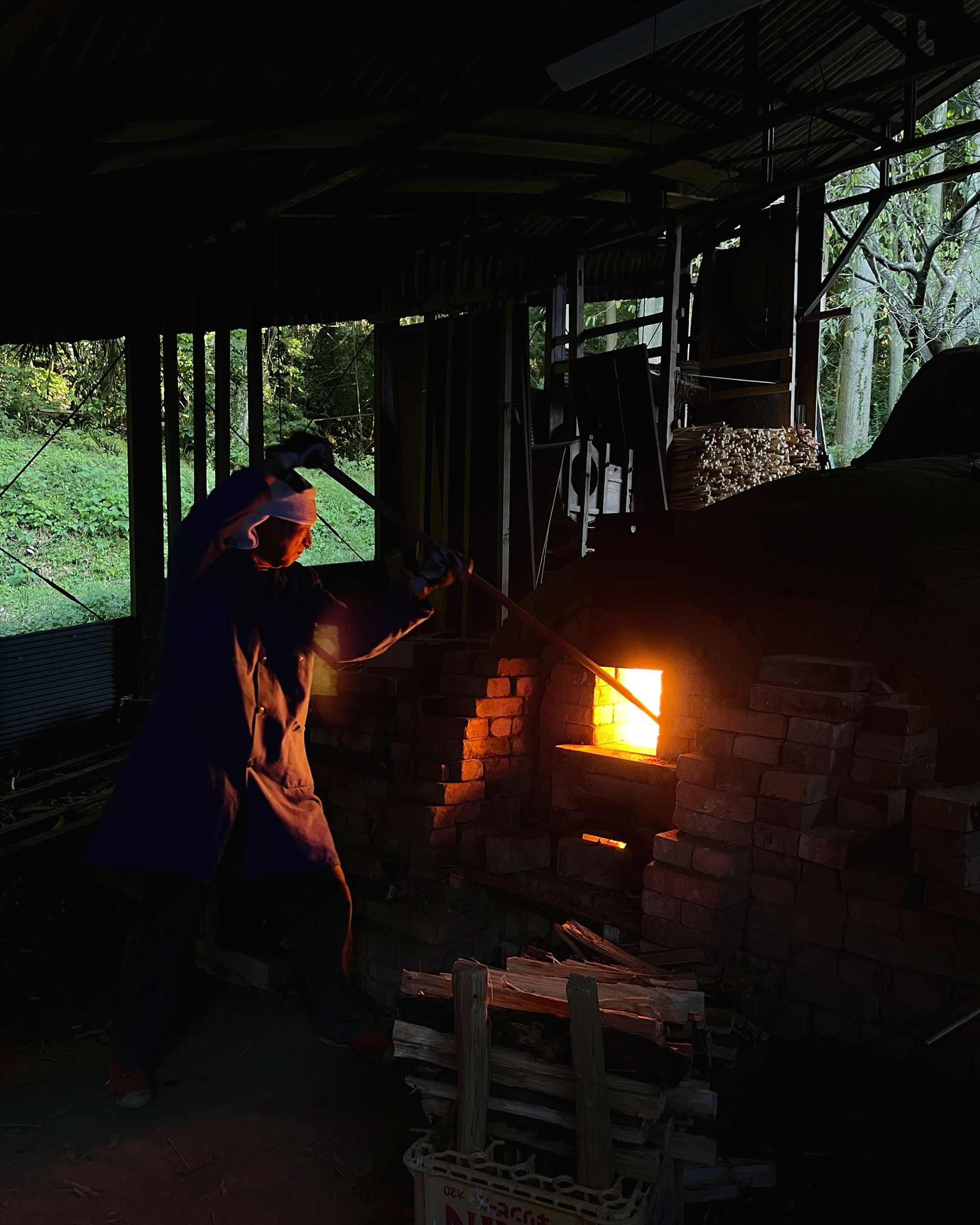 Keisuke Iwata holding a stick up high to stoke the fire of the anagama kiln