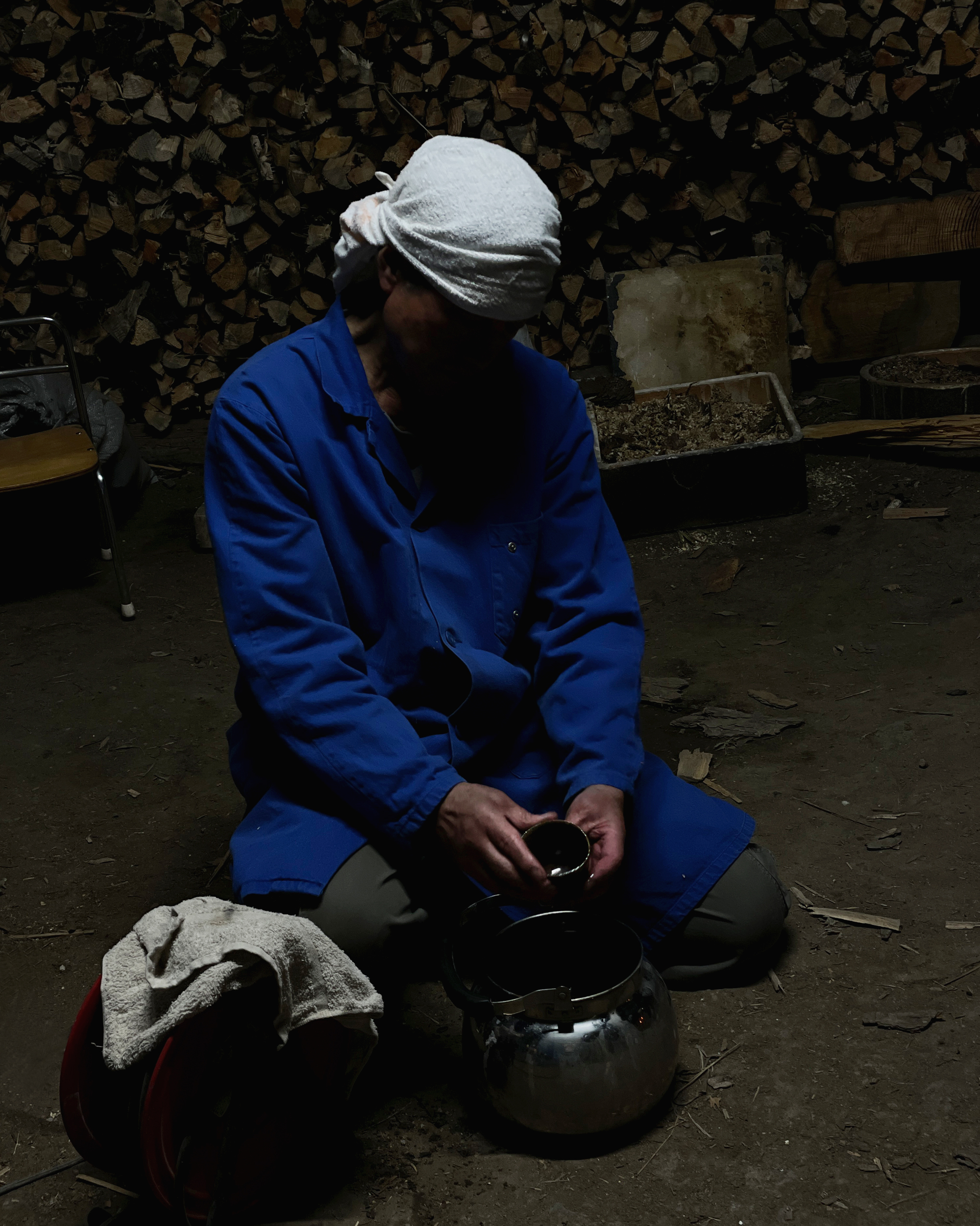 Keisuke Iwata in dark sahdows holding a black anagama sake cup and contemplating its appearance