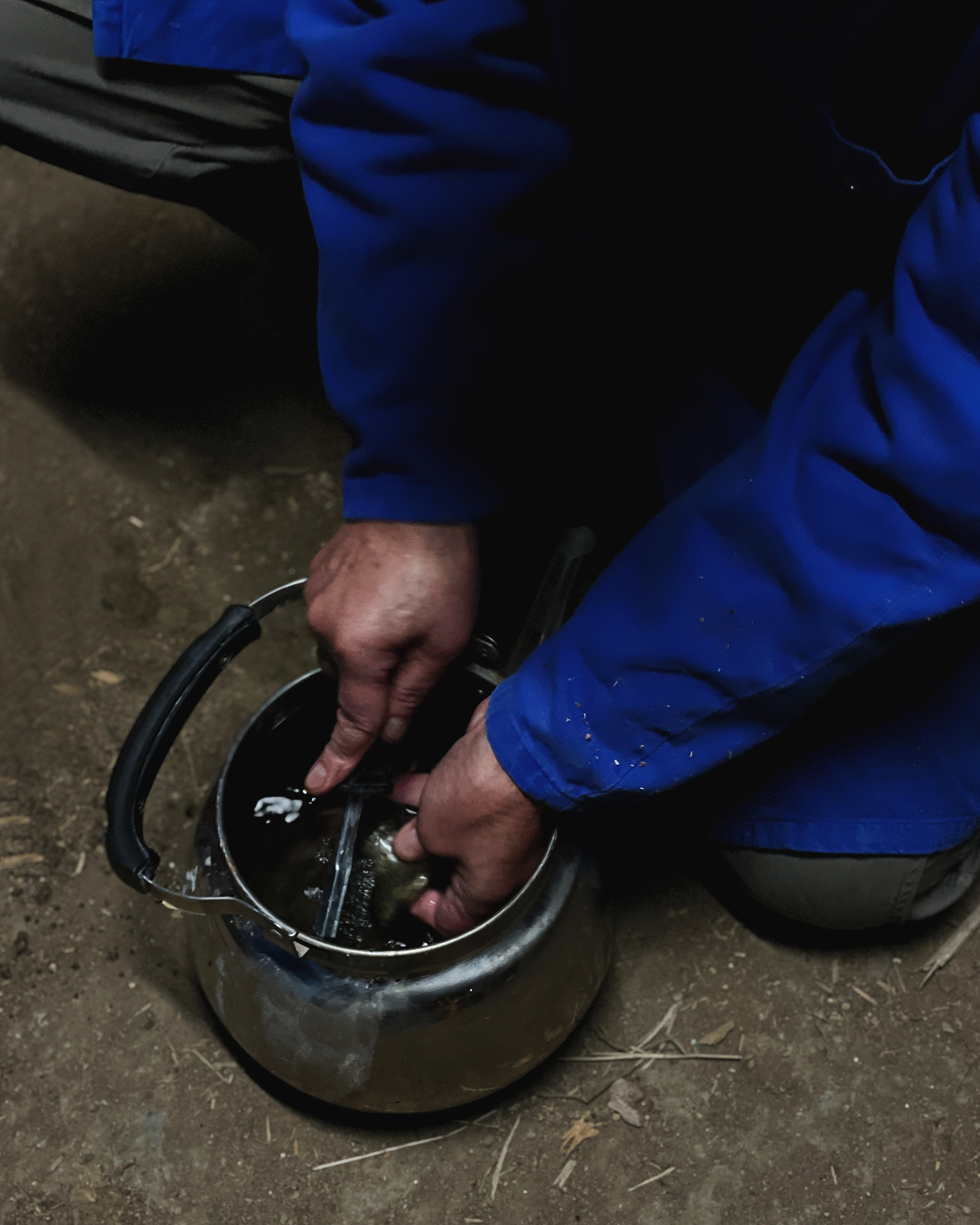 Close up of Keisuke Iwata's hands cleaning an anagama teacup in a teapot of water with a scrubbing tool