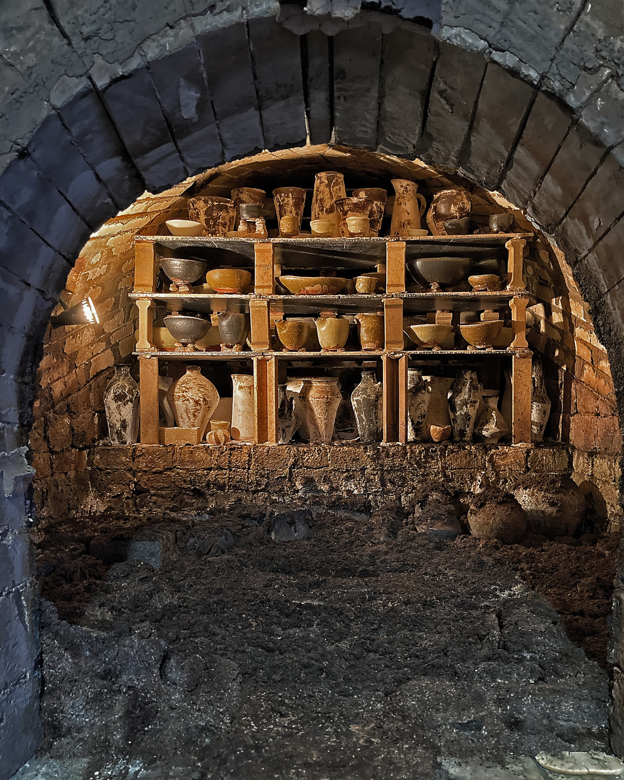 Anagama Kiln peek inside the arched entryway revealing shelves full of clay ceramics waiting to be fired