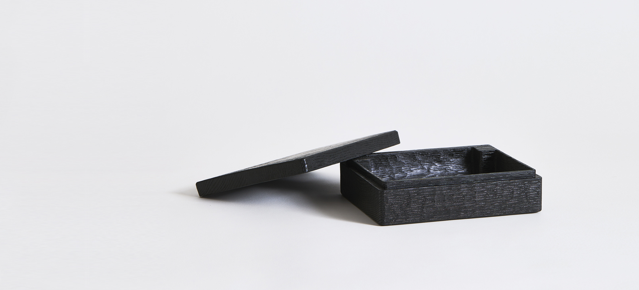 Opened black letter case with lid laying on the left side by Ryuji Mitani on a gray background