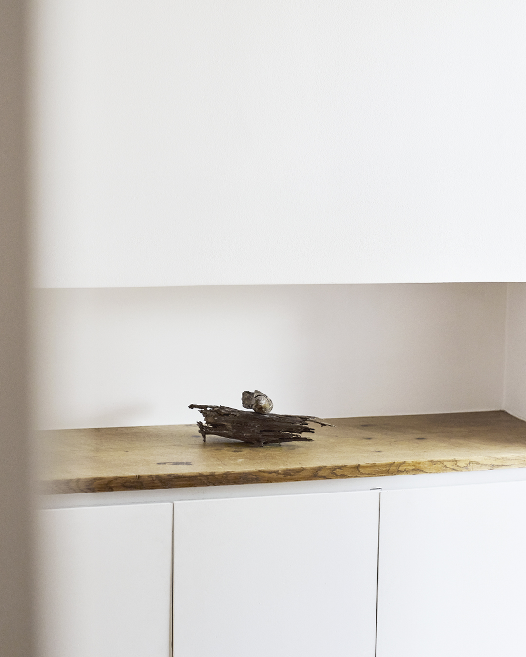 Peaking within a room, there's a sculptural wooden piece made by Ryuji MItani laying on a wooden counter.