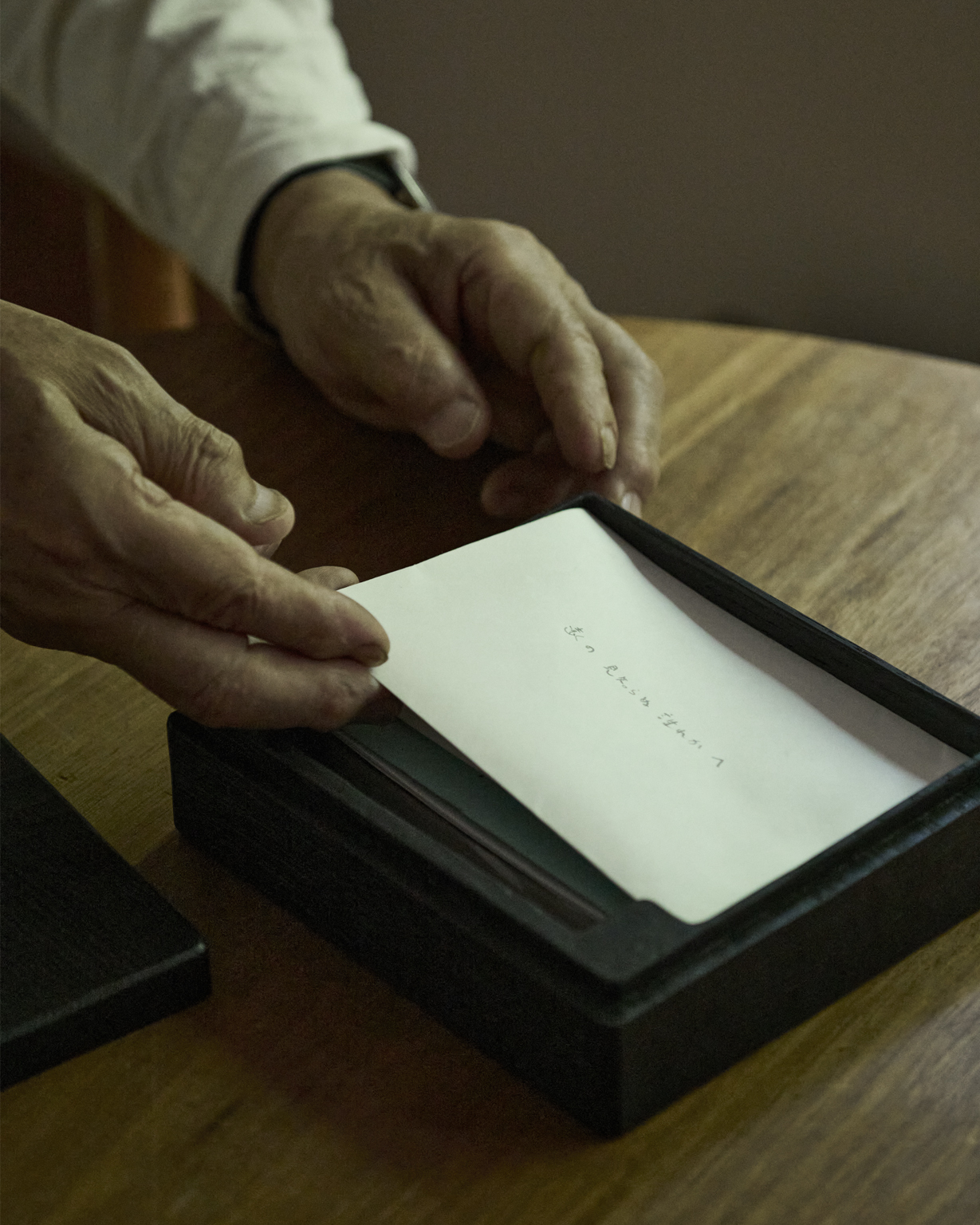 Opened wooden letter box made by Ryuji mitani with Mitani's hands pulling a letter out of the box
