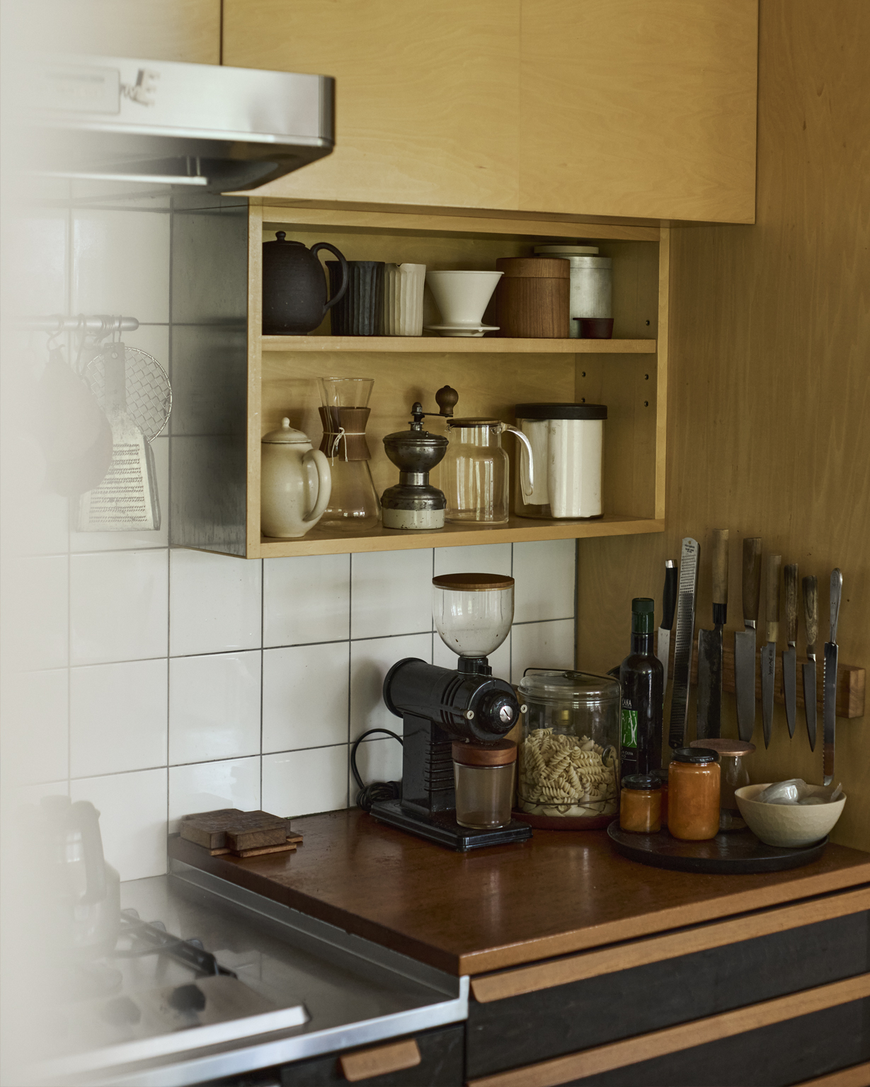 Ryuji Mitani's kitchen shelves and cabinets displaying his everyday things, including a wooden coffee canister made by himself