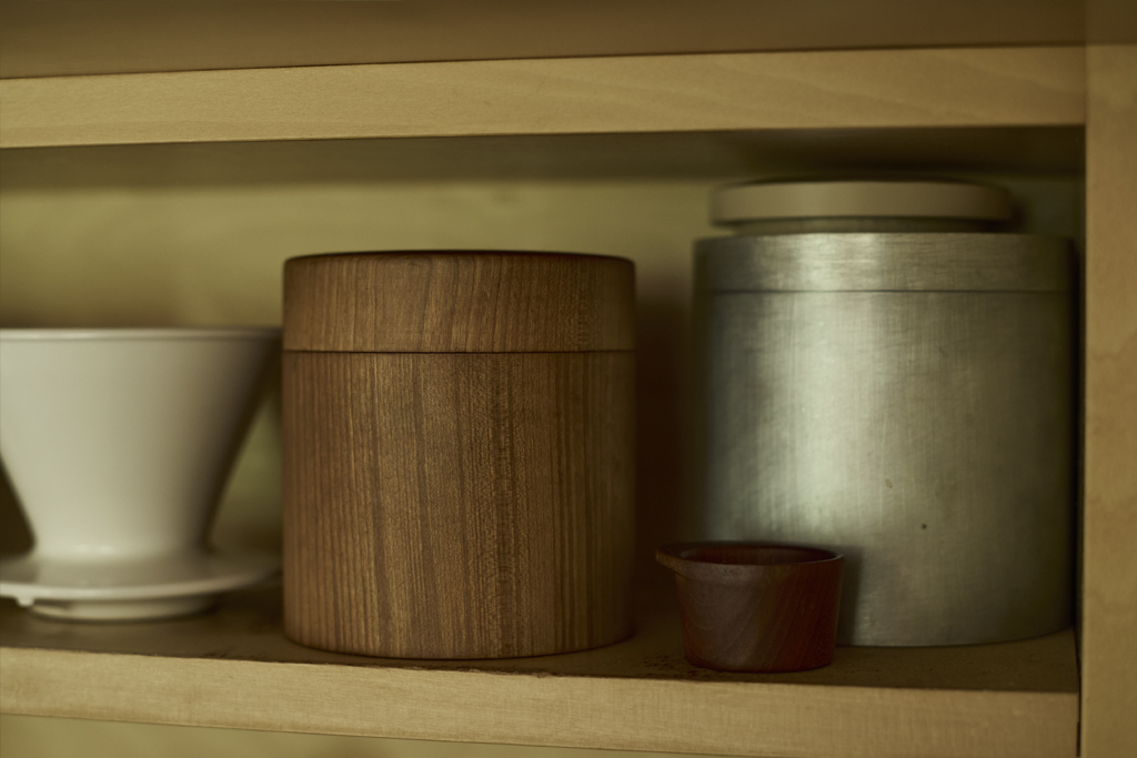 Up-close of Ryujij Mitani's shelf displaying a coffee canister and a small scoop made by mitani along with other everday items