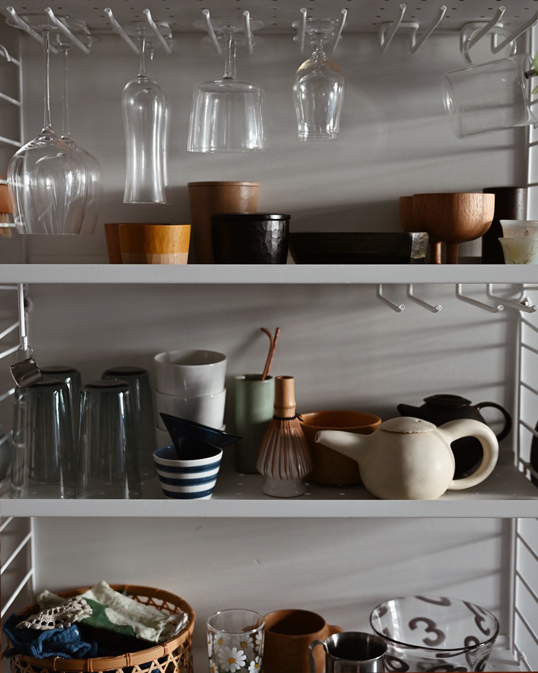 Tableware and teapots and glassware on a kitchen shelf
