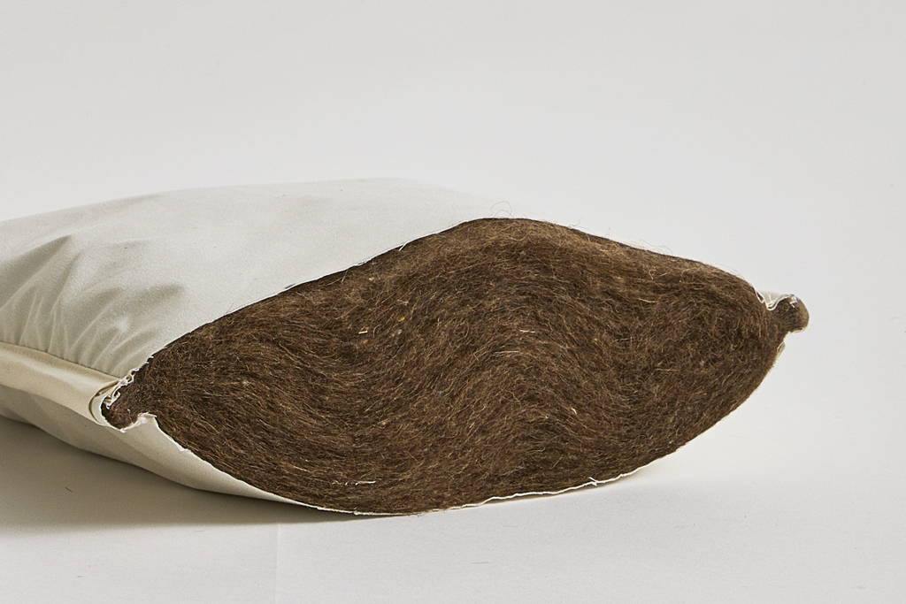 Up-close image of camel hair mattress pad interior by Iwata on a gray background