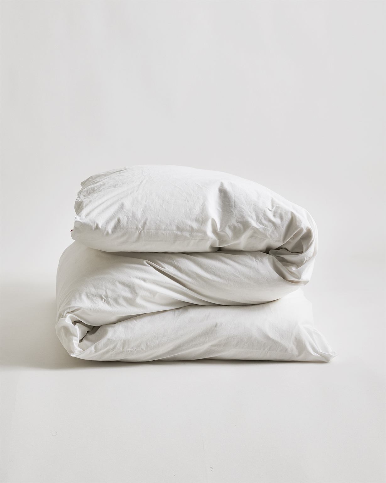 Folded cotton duvet sheet on duvet by Iwata on a gray background