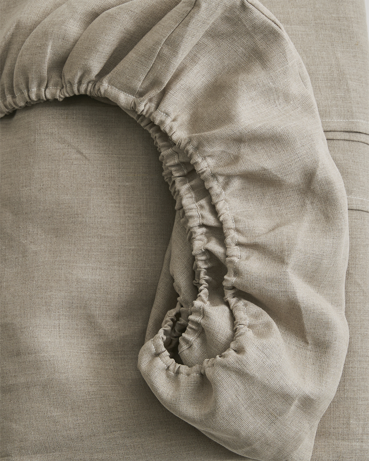 Up-close of unbleached linen fitted sheet by Iwata on a gray background