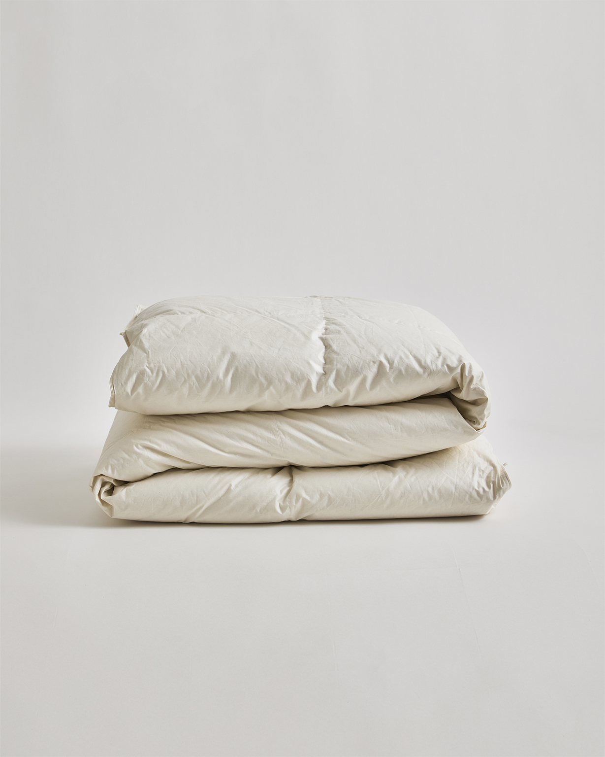 Folded unbleached duvet in heavy by Iwata on a gray background