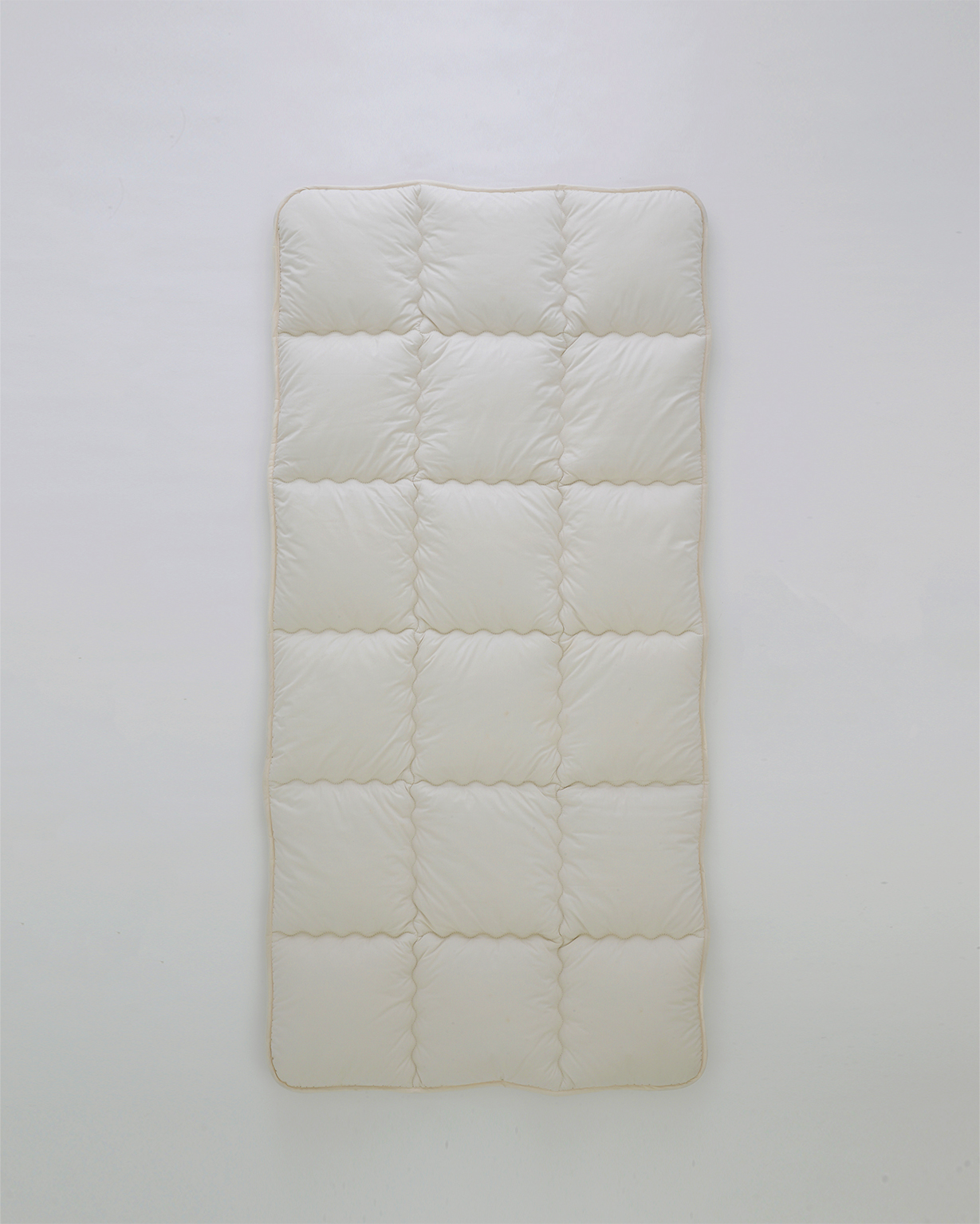 Camel hair mattress pad laid flat by Iwata on a gray background