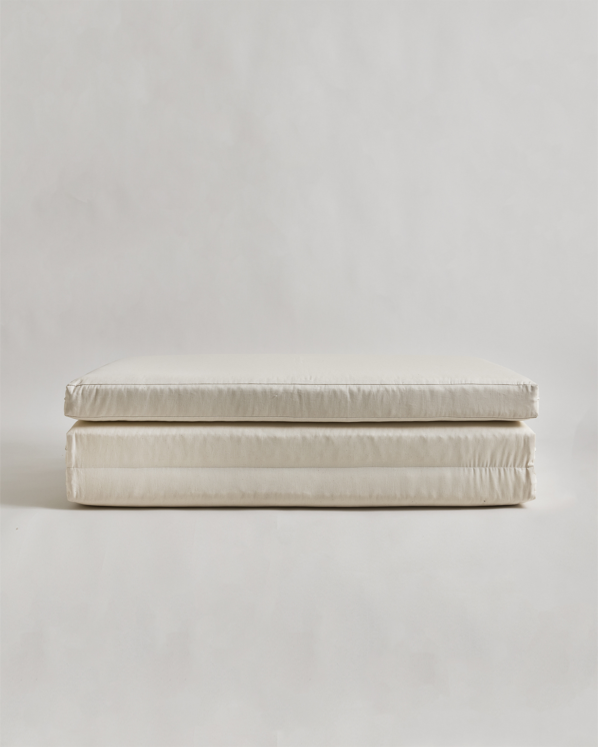 Folded futon floor pad by Iwata on a gray background