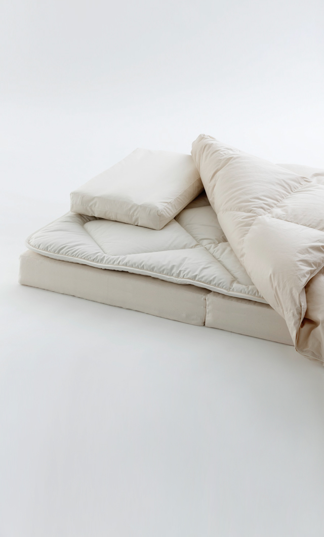 Cropped image of futon set by Iwata including floor pad, mattress pad, duvet, and pillow on a light gray background