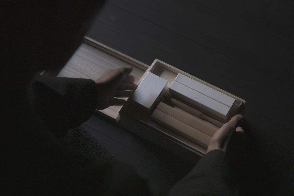 Figure picking up the first layer of the Nezen Boxed Set on a black background