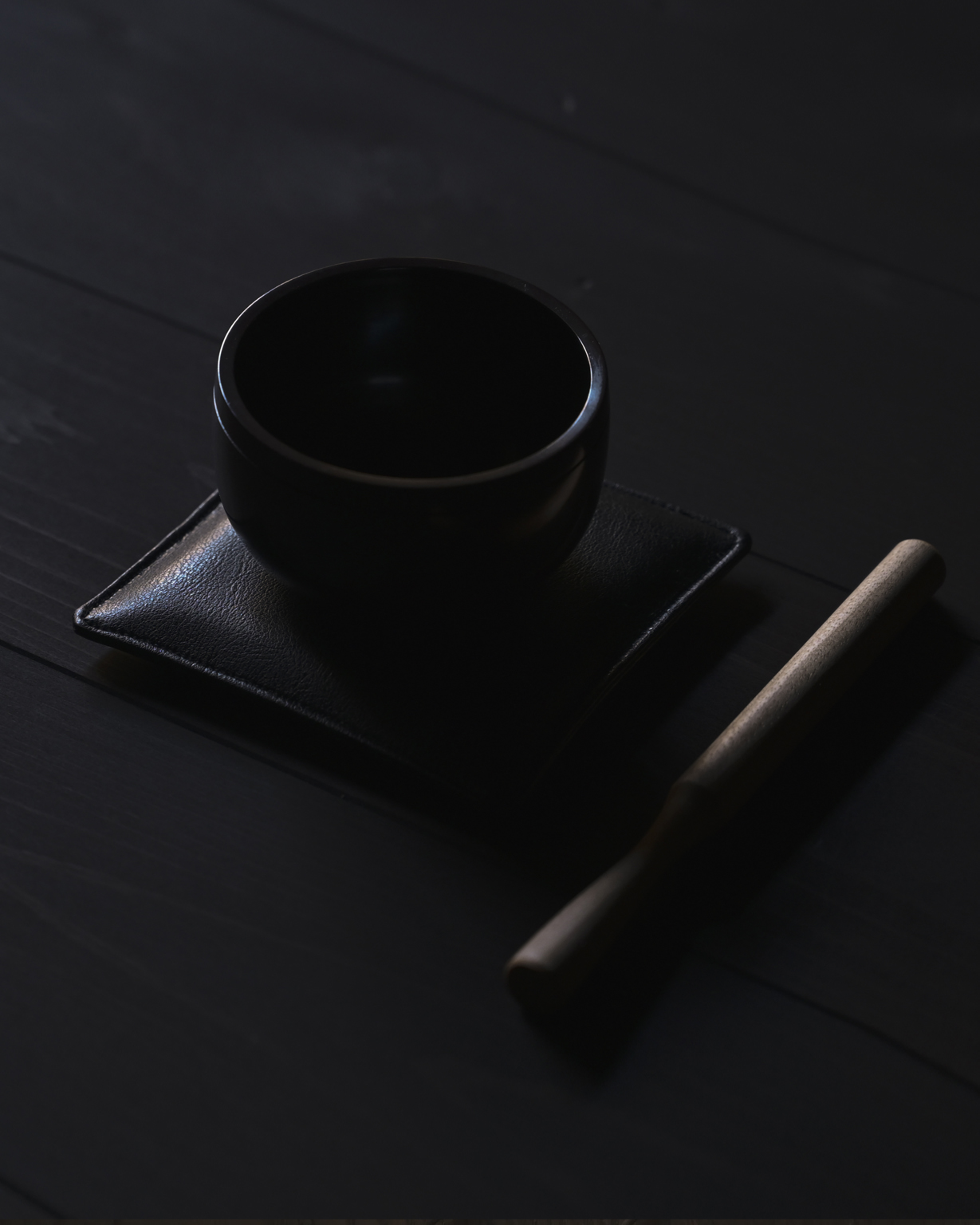 Oring Singing Bowl on a pad with handcarved wood striker beside it on a dark wood floor